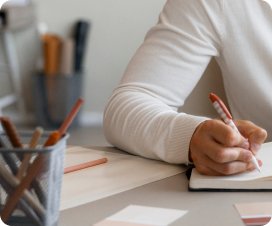 Aluna escrevendo em um caderno de metas semanais